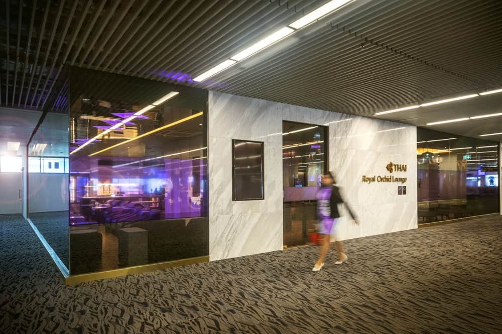 This is the exterior of the airport lounge with glass walls accented by the large white marble panel that also houses the main door.