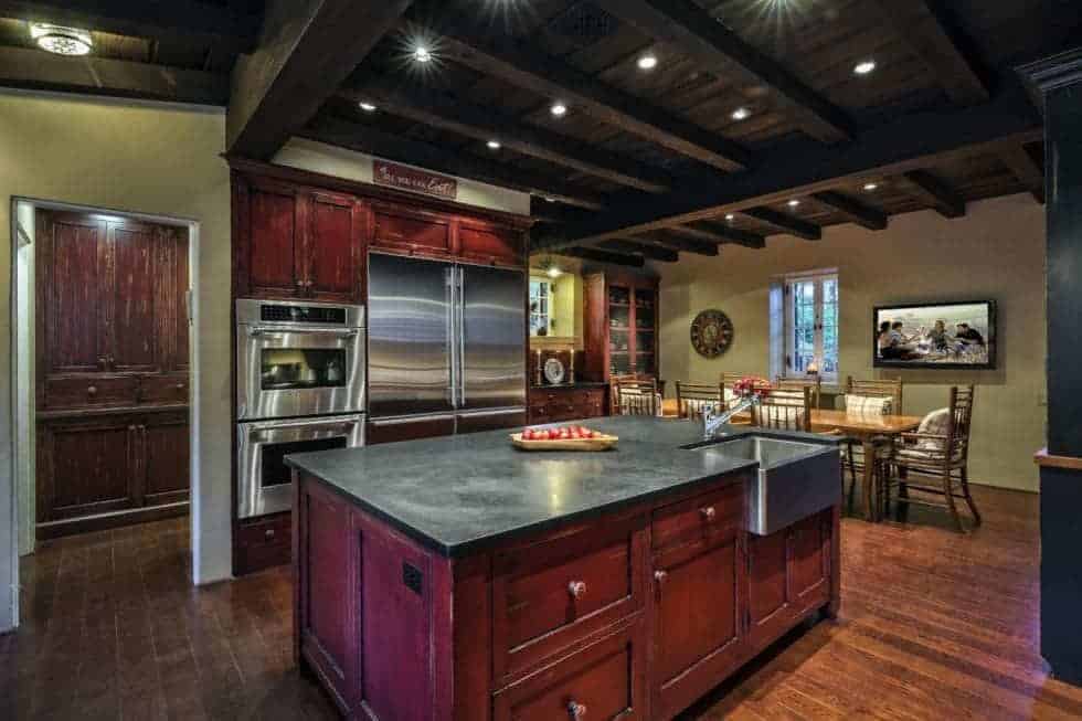This is the spacious kitchen with a tall beamed ceiling that has recessed lights. This is paired with redwood cabinetry that makes the stainless steel appliances stand out. Image courtesy of Toptenrealestatedeals.com.