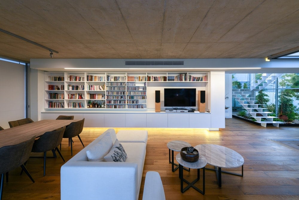 On the other side of the living room is a large walls with built-in wooden shelves and cabinets that serve as bookshelves and entertainment cabinet.