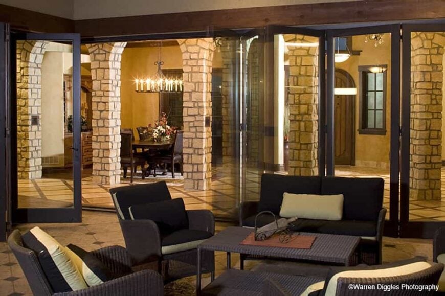 Folding glass doors open to the covered patio that's filled with wicker seats and a matching table.