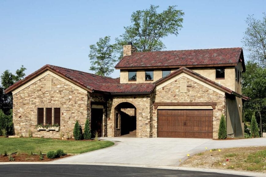 Front exterior view showing the stone and stucco siding, three-car garage, and an arched entryway.