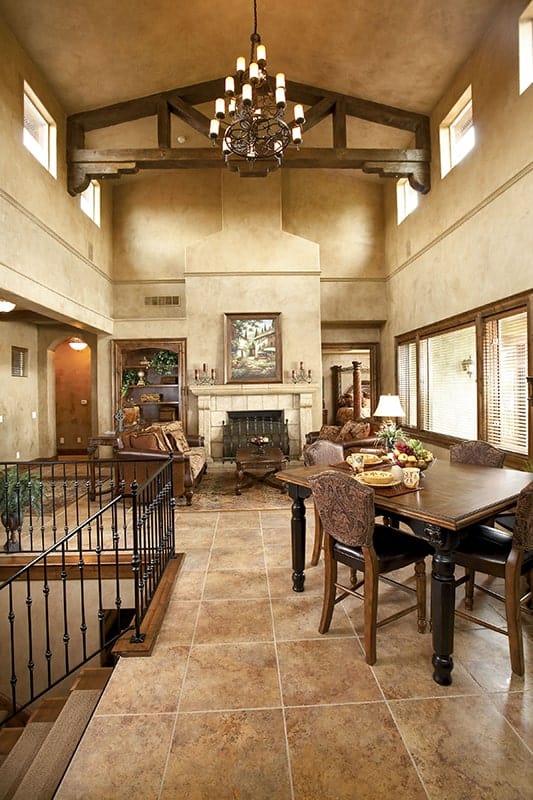 Shared dining and living room with marble tiled flooring and a vaulted ceiling with exposed decorative beams.