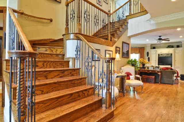 Winding staircase with ornate spindles and wooden steps that match the hardwood flooring.