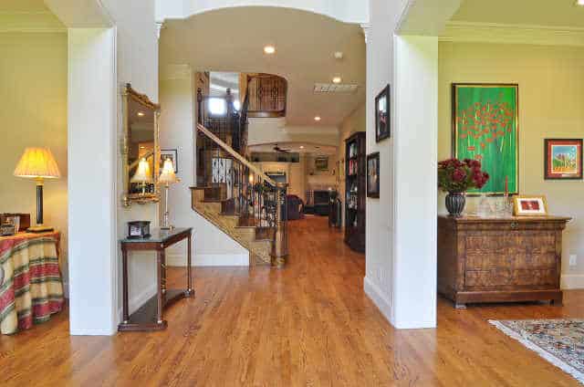 Foyer with wooden console table, gilded mirror, and an open archway leading to the living room.