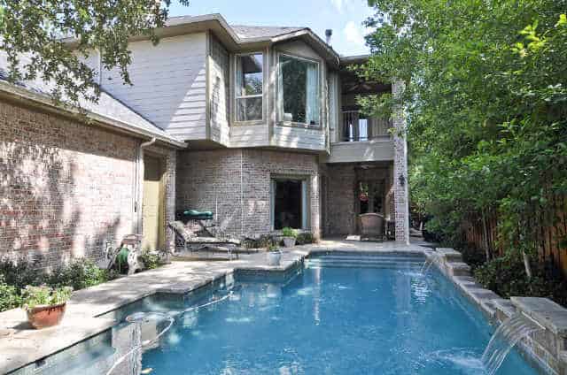 The backyard is filled with a covered patio, a swimming pool, and a double garage.