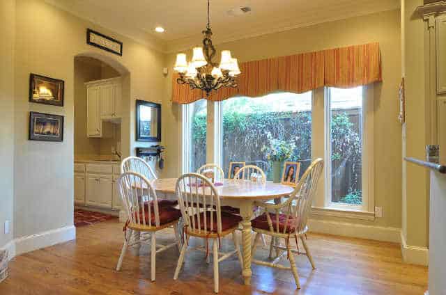Breakfast nook with round back chairs, an oval dining table, and a classic chandelier.