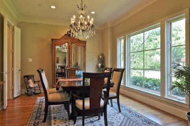 Formal dining room with a dark wood dining set, a bordered area rug, crystal chandelier, and a rocking chair that sits next to the cabinet.Formal dining room with a dark wood dining set, a bordered area rug, crystal chandelier, and a rocking chair that sits next to the cabinet.