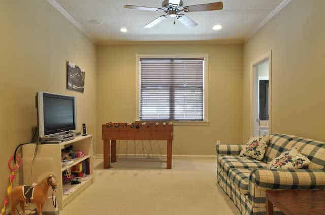 Recreation room with a checkered sofa, game table, a TV, and a ceiling fan.