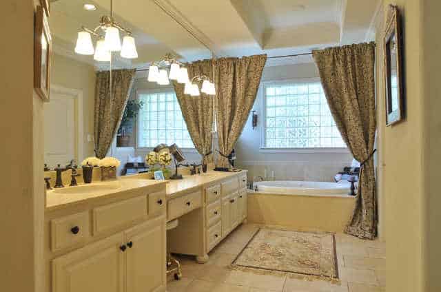 The primary bathroom is equipped with dual sink vanity and a drop-in bathtub that's placed under the glass block window.
