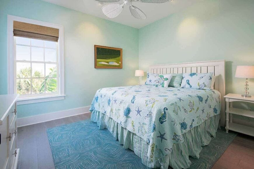 This bedroom offers white furnishings, a blue patterned rug, and a ceiling fan mounted on the regular ceiling.
