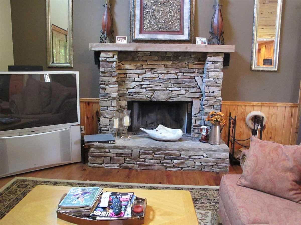 A closer look at the stone fireplace topped by ornate candle holders and a framed artwork.