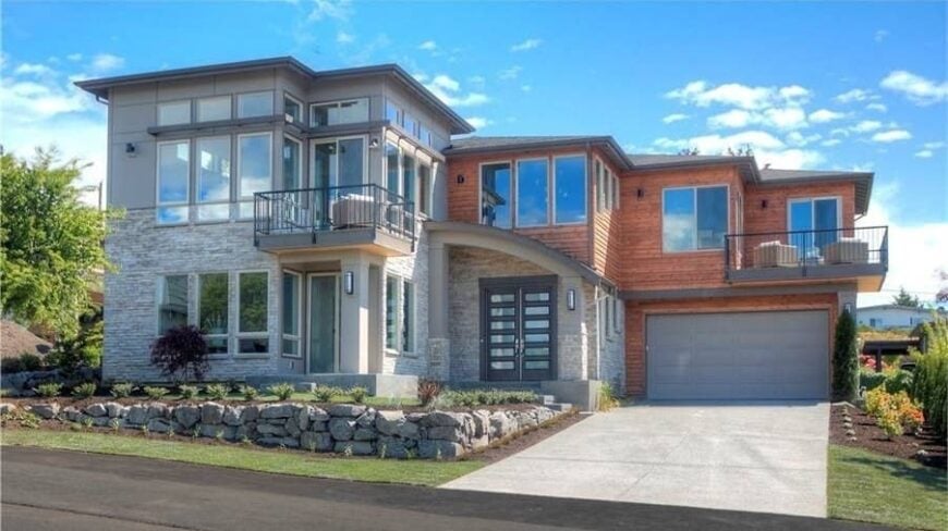 Front exterior view with wood and stone cladding, upper decks, and a striking entry with a french front door.