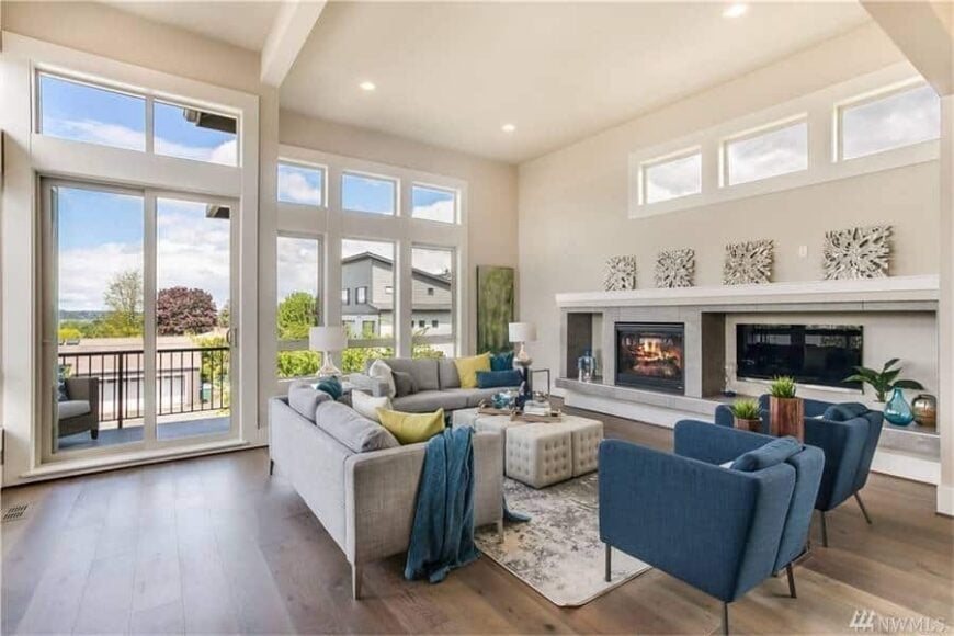 The living room has gray sofas, blue armchairs, a modern fireplace, and a wall-mounted TV.
