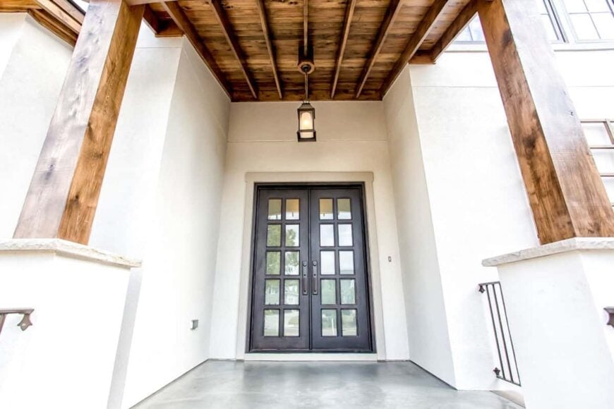 Covered entry with a french front door, tapered columns, and a beamed ceiling with a hanging lantern pendant.