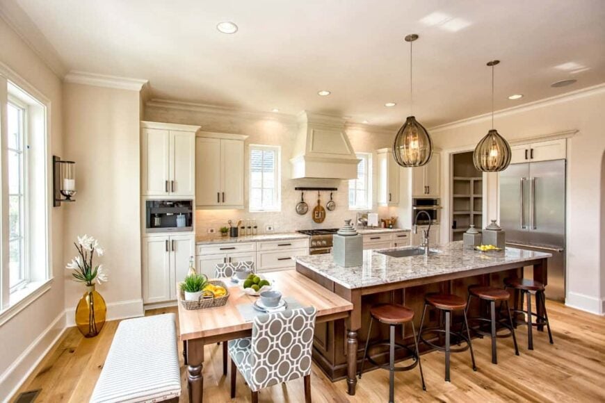 Eat-in kitchen with white cabinetry, stainless steel appliances, granite countertops, and a breakfast island attached with an eating counter.