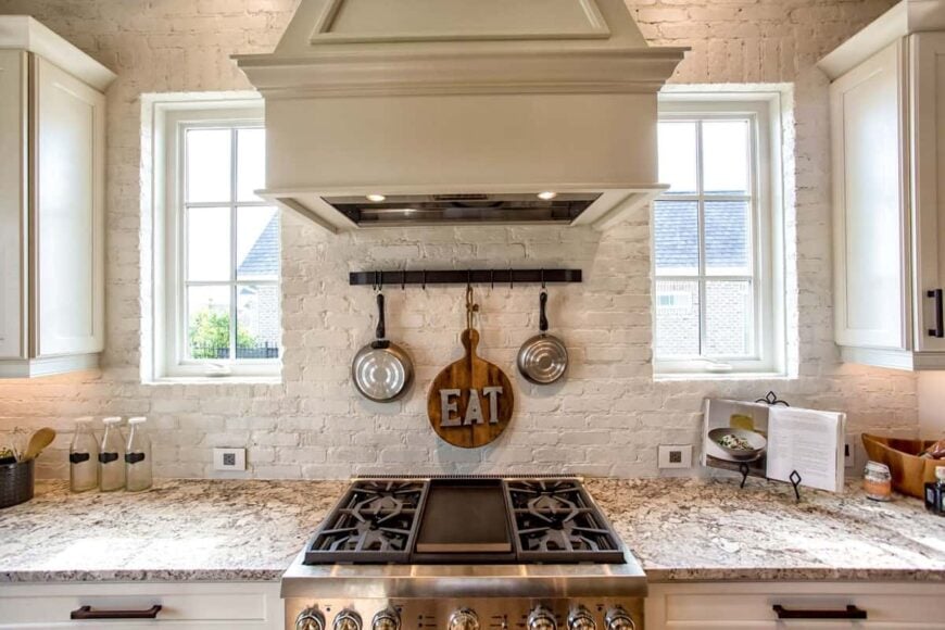 White framed windows flank the bespoke hood that's fixed above the cooktop.