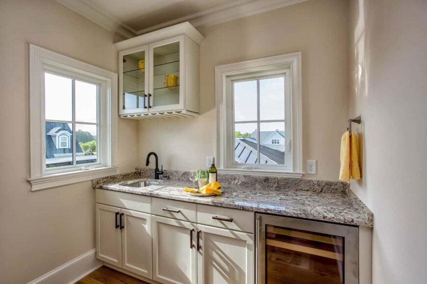 Wet bar with granite countertop, white cabinets, and a wine fridge.