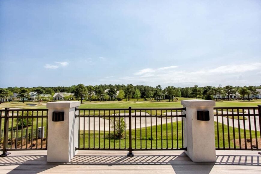 The balcony with wrought iron railings overlooks the expansive greenery.