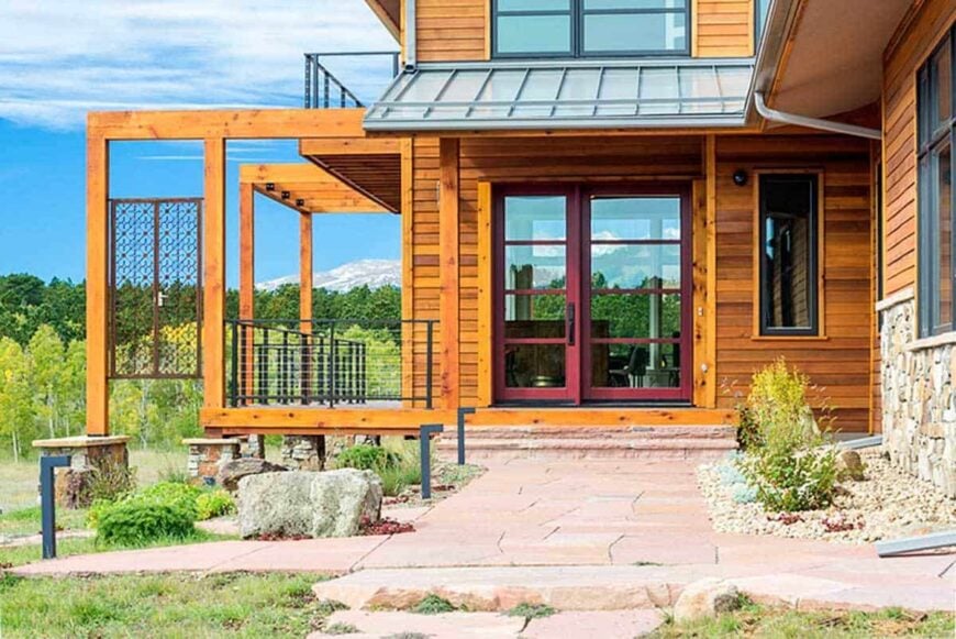 Home entry with a red-framed glass door that stands out against the wooden exterior walls.