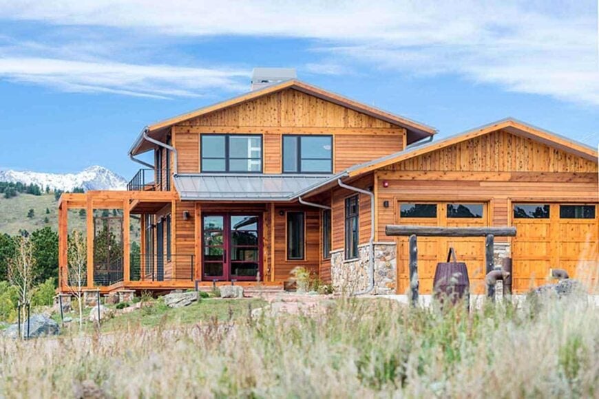 Home facade showcasing a wood cladding, stone accents, and tinted glazed windows.