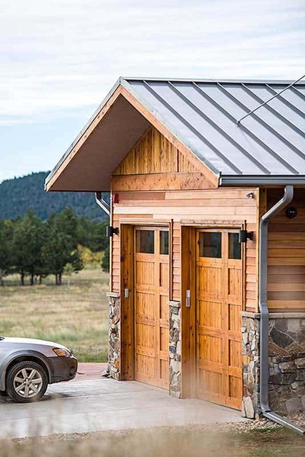 The double garage has a gable roof, stone accents, and wooden doors that blend in with the walls.