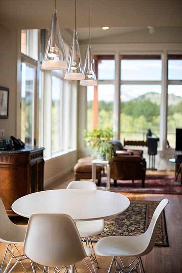Dining area with white modern chairs, a round dining table, and cone glass pendants.