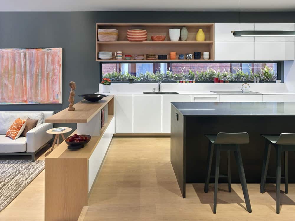 This is the kitchen with a large L-shaped peninsula and a dark kitchen island that stands out against the hardwood flooring and white cabinetry.