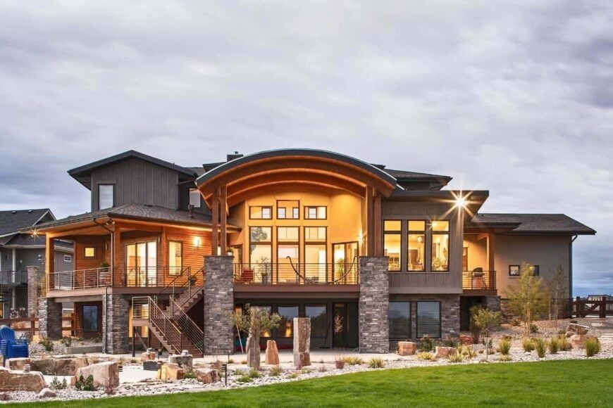 Rear exterior view showing the covered patio and expansive deck supported by stone columns.