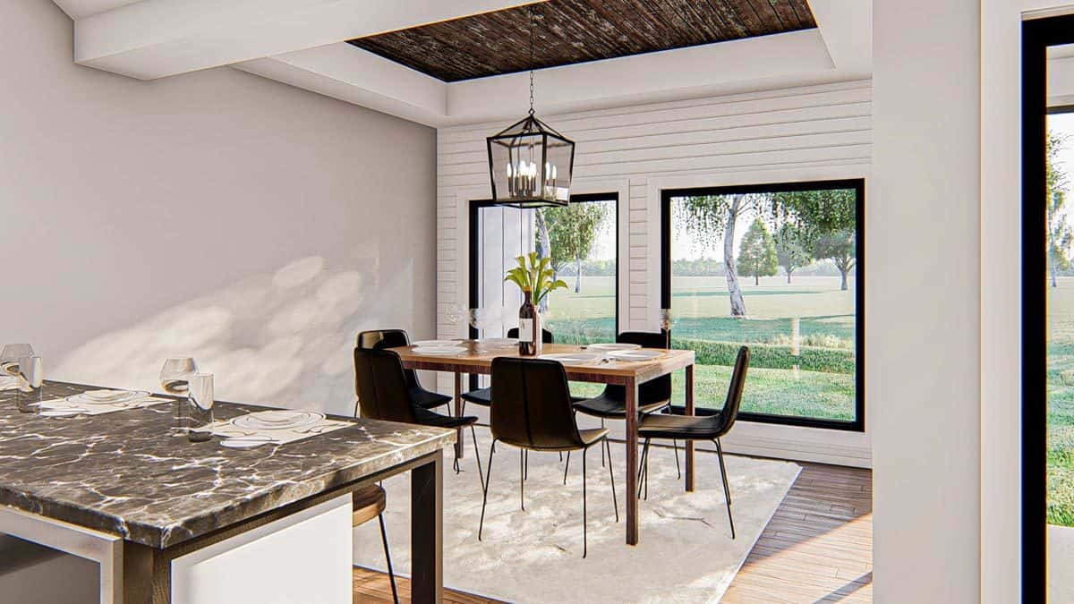 Breakfast nook with black modern chairs, a beige area rug, a wooden dining table, and a lantern pendant hanging from the tray ceiling.