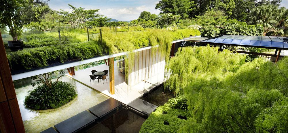 This is a look at the ground floor from the vantage of the second-floor balcony that is has its own lush landscaping of shrubs that seem to waterfall below.