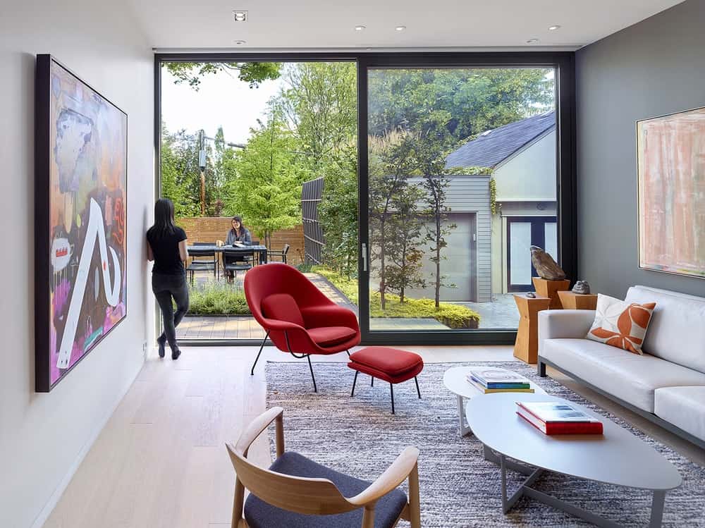 This is the bright living room with a large sliding glass wall on the far side illuminating the sofa set across from the large colorful painting.