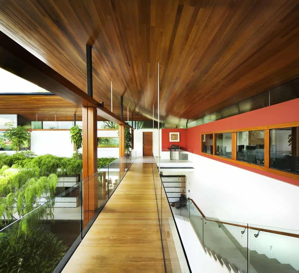 This is the second-floor landing with a long and narrow hallway of hardwood flooring topped iwth a shed wooden ceiling and has glass walls on its indoor balcony.