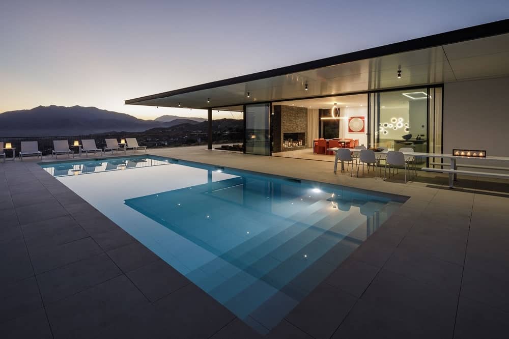 This is a view of the house from the vantage of the poolside area that is open to the interiors with glass walls that slide open. This area also has a sweeping view beyond the pool.