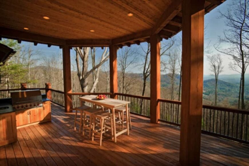 The covered deck is filled with a summer kitchen and an outdoor dining set.