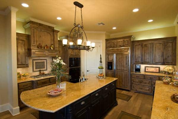 The kitchen is equipped with granite countertops, black appliances, wooden cabinetry, an ornate chandelier, and a large center island.
