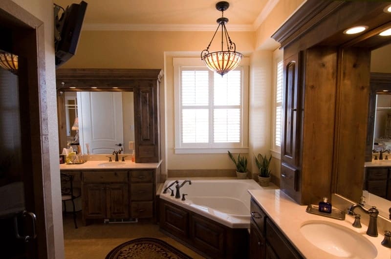 The primary bathroom offers a walk-in shower, separate his and her vanities, and a corner tub well-lit by a dome pendant.