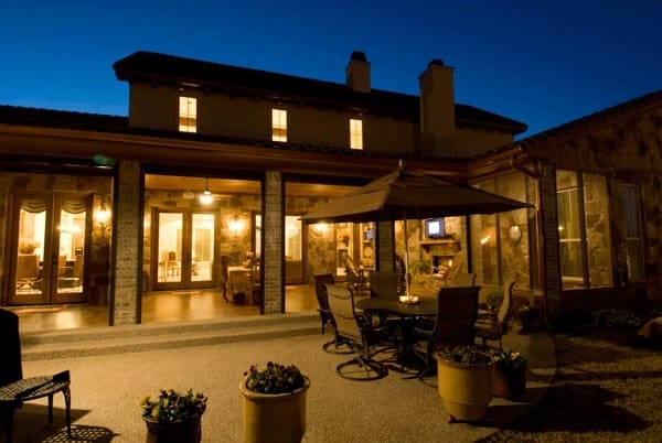 Rear exterior view showing the open patio and covered porch lined with stone columns.