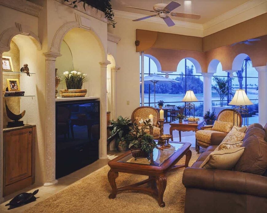 Living room with a leather sofa, round back armchairs, a glass top coffee table, and a flatscreen TV.