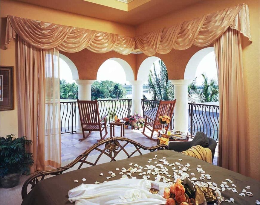 The guest bedroom has a cozy bed and a private balcony filled with wooden rocking chairs.