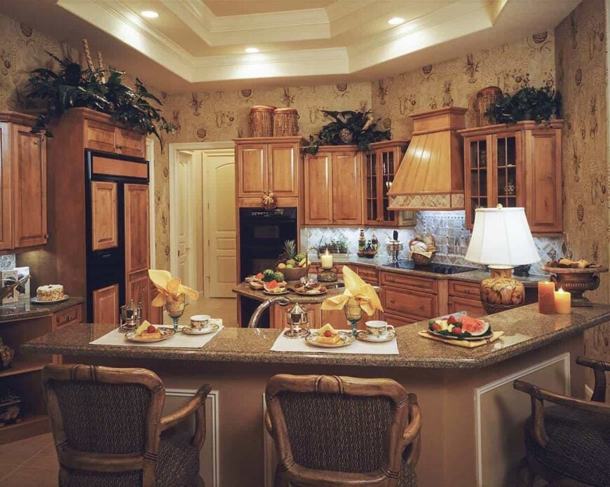 The kitchen is equipped with wooden cabinetry, black appliances, granite countertops, a small center island, and a curved peninsula.