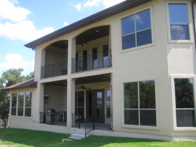 Rear exterior view showing the covered porch and balcony framed with wrought iron railings.