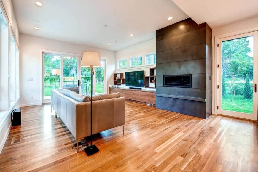 The living room has a modern fireplace, a wall-mounted TV, and a gray sofa lit by traditional floor lamps.