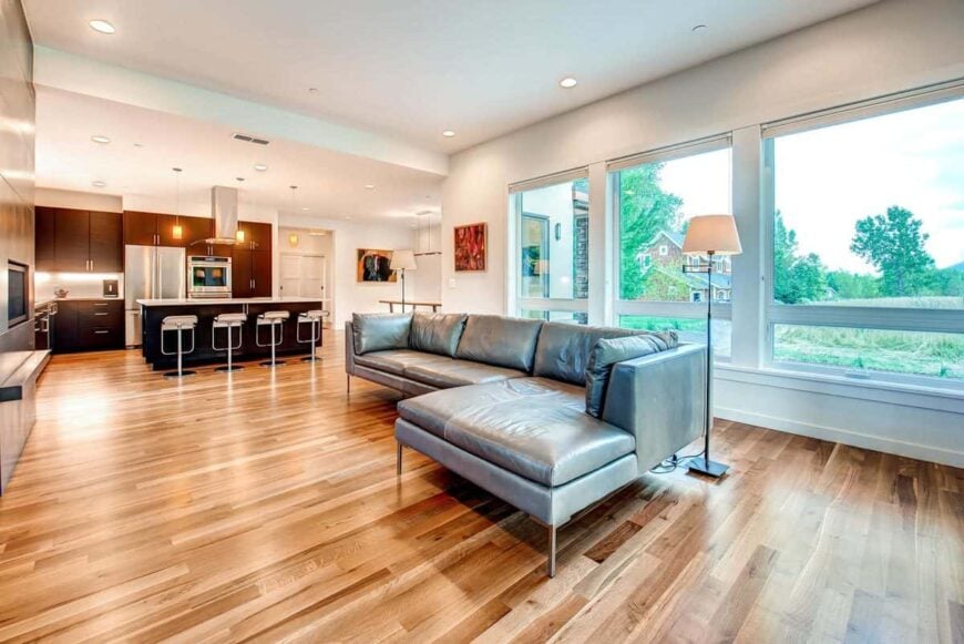 Three-panel glass windows at the back of the L-shaped sofa bring natural light in.