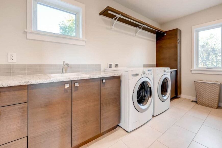The laundry room is equipped with white front-load appliances, wooden cabinets, and a porcelain sink.