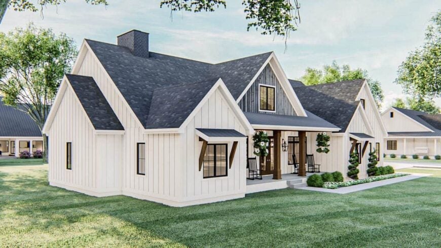 Angled front view showing the white vertical siding, gable rooflines, and a covered porch lined with rustic columns.