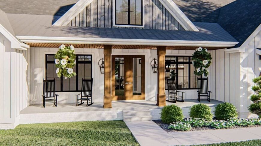 The front covered porch is filled with dark wood rocking chairs and fresh hanging plants.