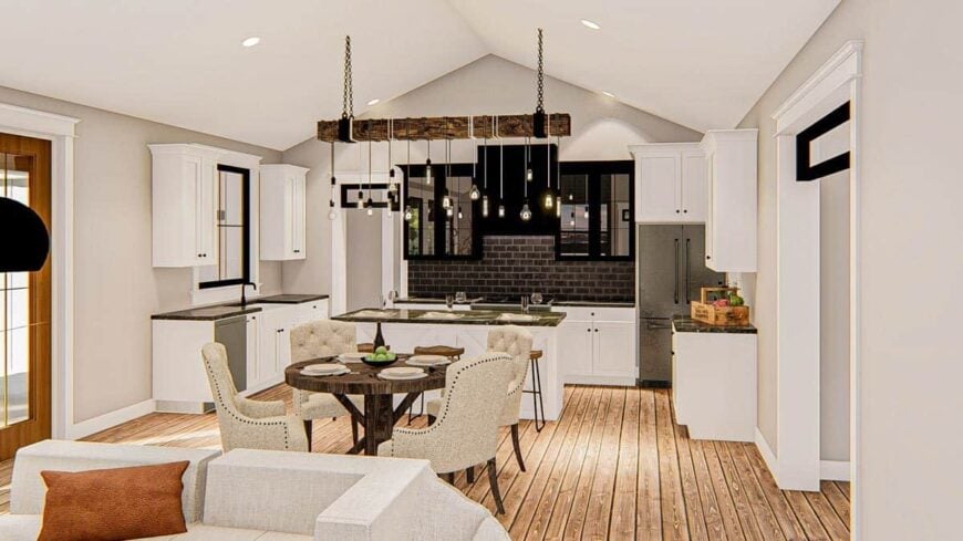 The kitchen at the far end is equipped with slate appliances, granite countertops, black subway tile backsplash, and a center island lit by bulb pendants hanging from the rustic beam.