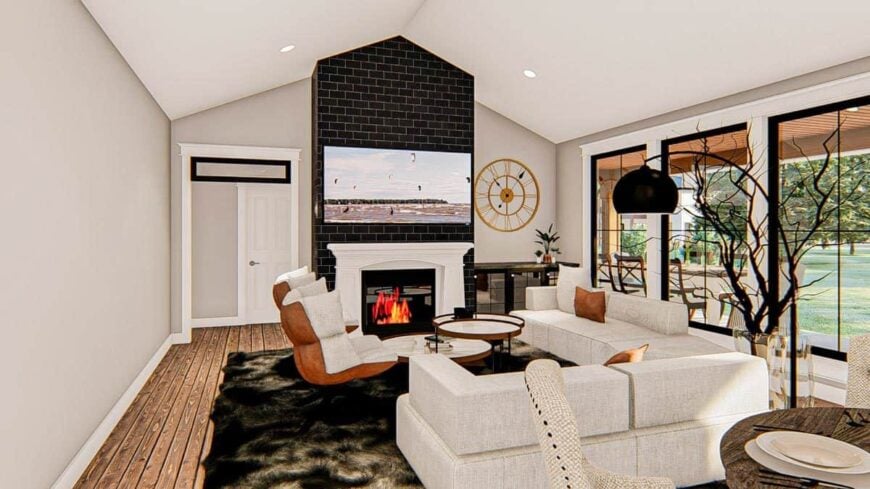 Living room with light gray sectionals, cushioned chairs, a modular coffee table, and a fireplace with a TV on top.