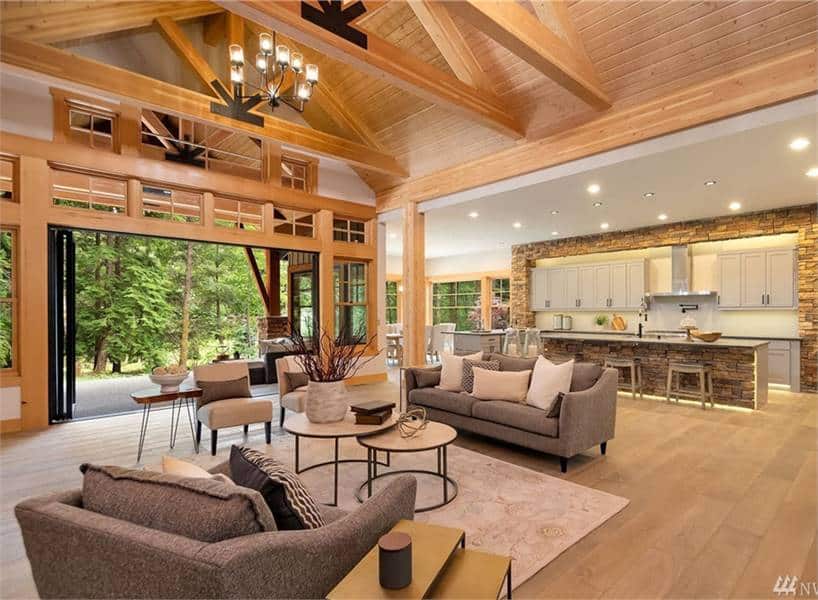 An open layout view showing the living room, kitchen, dining area, and outdoor living accessible via the folding glass doors.