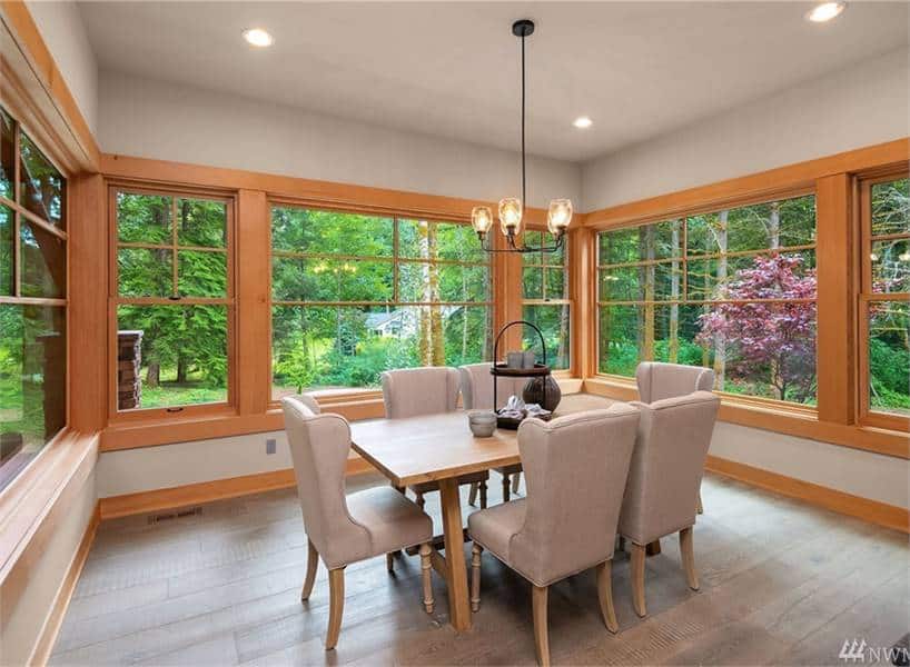 The dining area offers a wooden dining table, gray wingback chairs, and a warm glass chandelier.